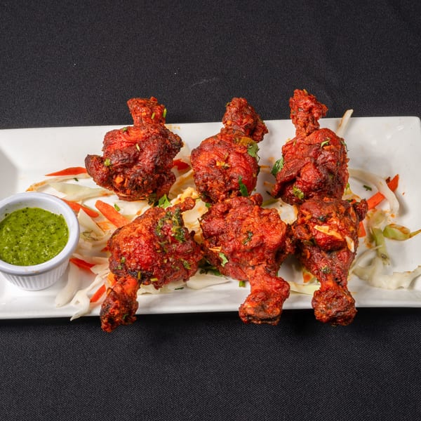 Saffron Indian Cuisine's Chicken Lollipop, six pieces of fried chicken drumettes with green chutney.
